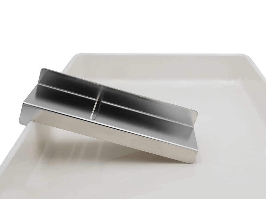 Heavy-duty bladeless stainless steel soap planer hooked on the edge of a pizza dough proof tray for effortless trimming.
